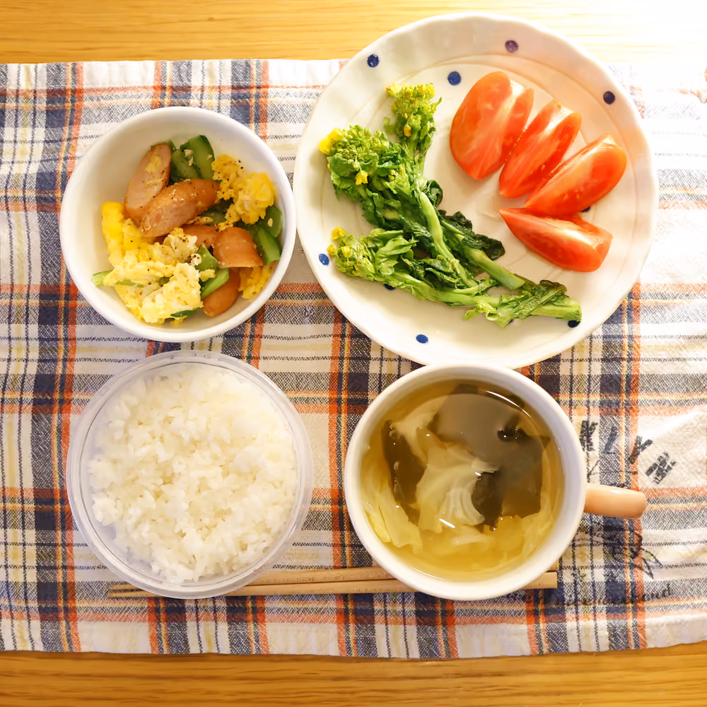 ごはん、ソーセージと卵ときゅうりの炒め物、菜の花、トマト、わかめと野菜のスープ